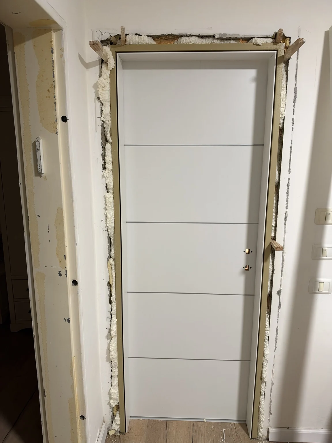 דלת פנים מעוצבת לבנה עם פסי רוחב – במהלך התקנה בשטח