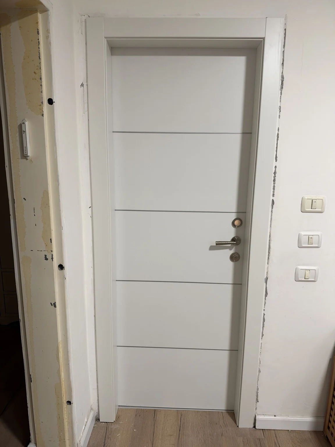 דלת פנים מעוצבת לבנה עם פסי רוחב – לאחר התקנה וגימור המשקוף